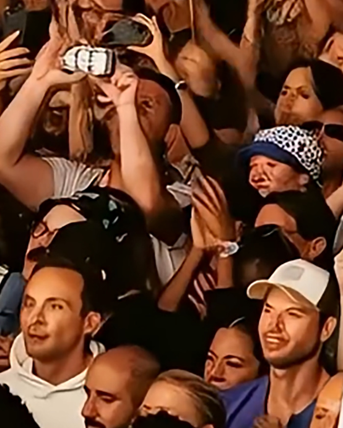 Crowd with raised hands and smartphones recording, illustrating AI-faked crowds and twenty-fingered hands controversy. Crowd with raised hands and smartphones recording, illustrating AI-faked crowds and twenty-fingered hands controversy.