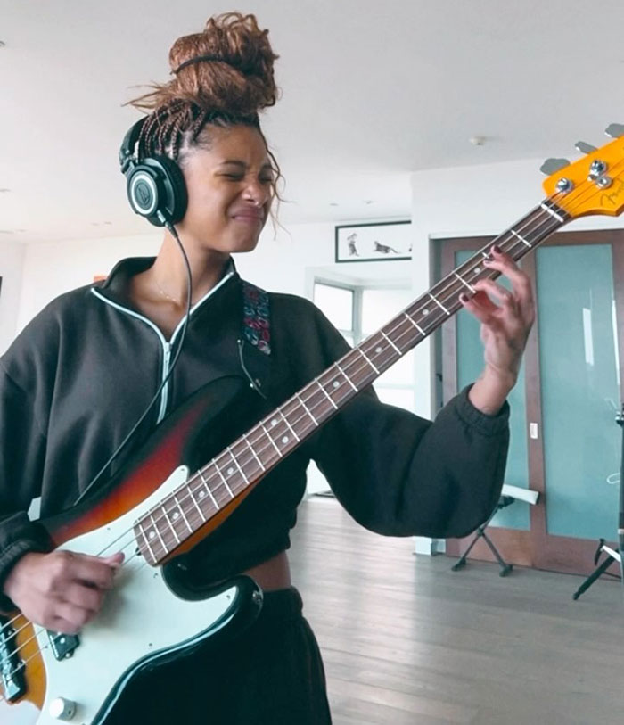 Will Smith and Jada Pinkett's daughter playing guitar with headphones on, showing intense expression indoors. Will Smith and Jada Pinkett's daughter playing guitar with headphones on, showing intense expression indoors.