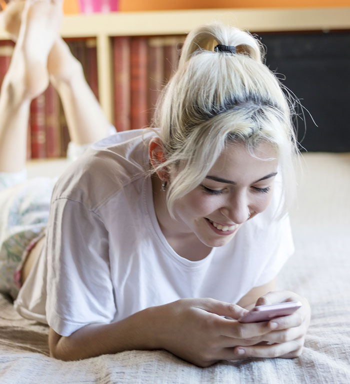 Young woman smiling while texting on phone, illustrating netizens reacting to AI boyfriend proposal news. Young woman smiling while texting on phone, illustrating netizens reacting to AI boyfriend proposal news.
