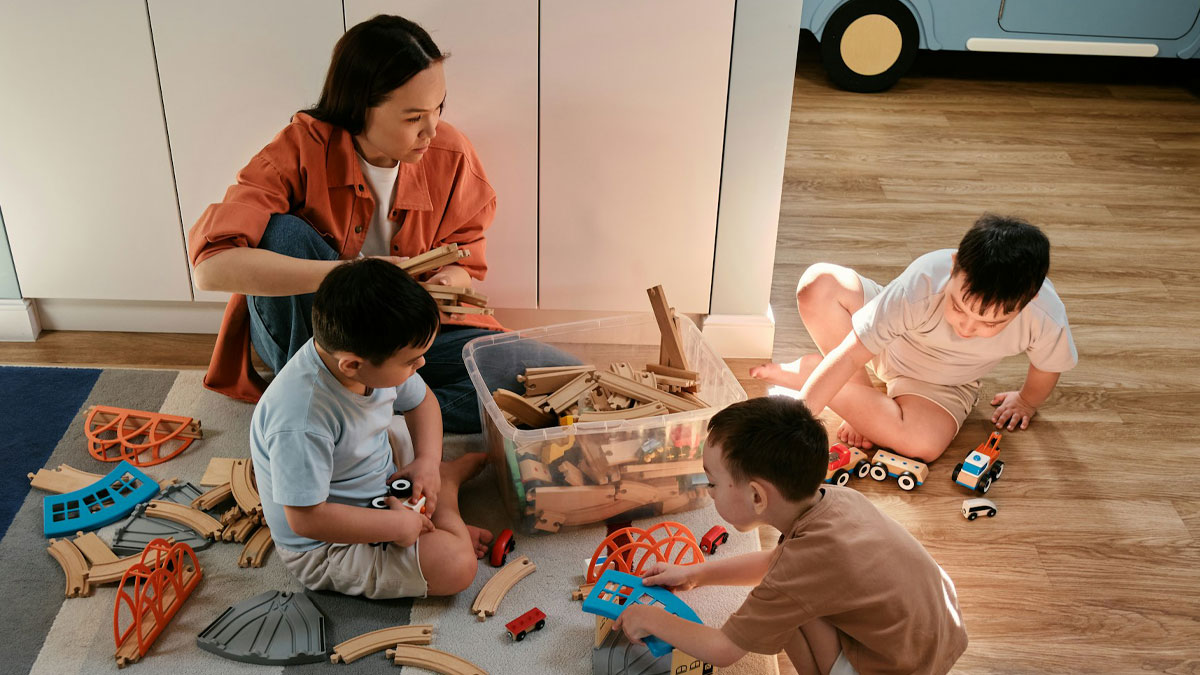 Woman babysitter playing with children on floor, demonstrating the value of babysitters and living wage importance