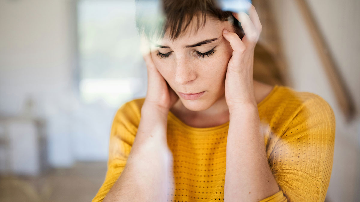 Worried mom-to-be in yellow sweater holding her head, reflecting on strange text about fiancu00e9 and her gut feelings.