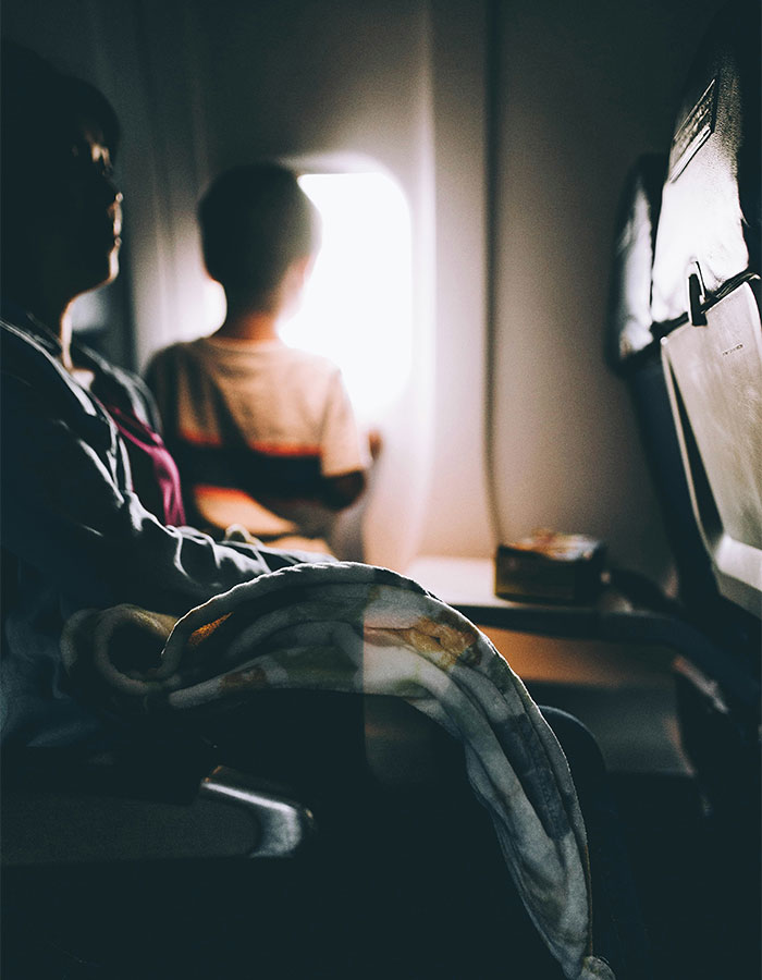 Passenger and child on flight, child looking out window, highlighting passenger's worst experience with bored child in flight debate. Passenger and child on flight, child looking out window, highlighting passenger's worst experience with bored child in flight debate.