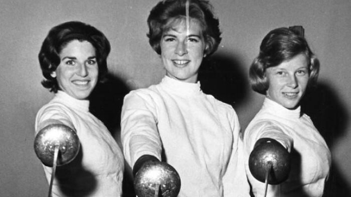 Three LA women in 1962 wearing fencing gear, holding foils and smiling, showcasing women living their best lives.