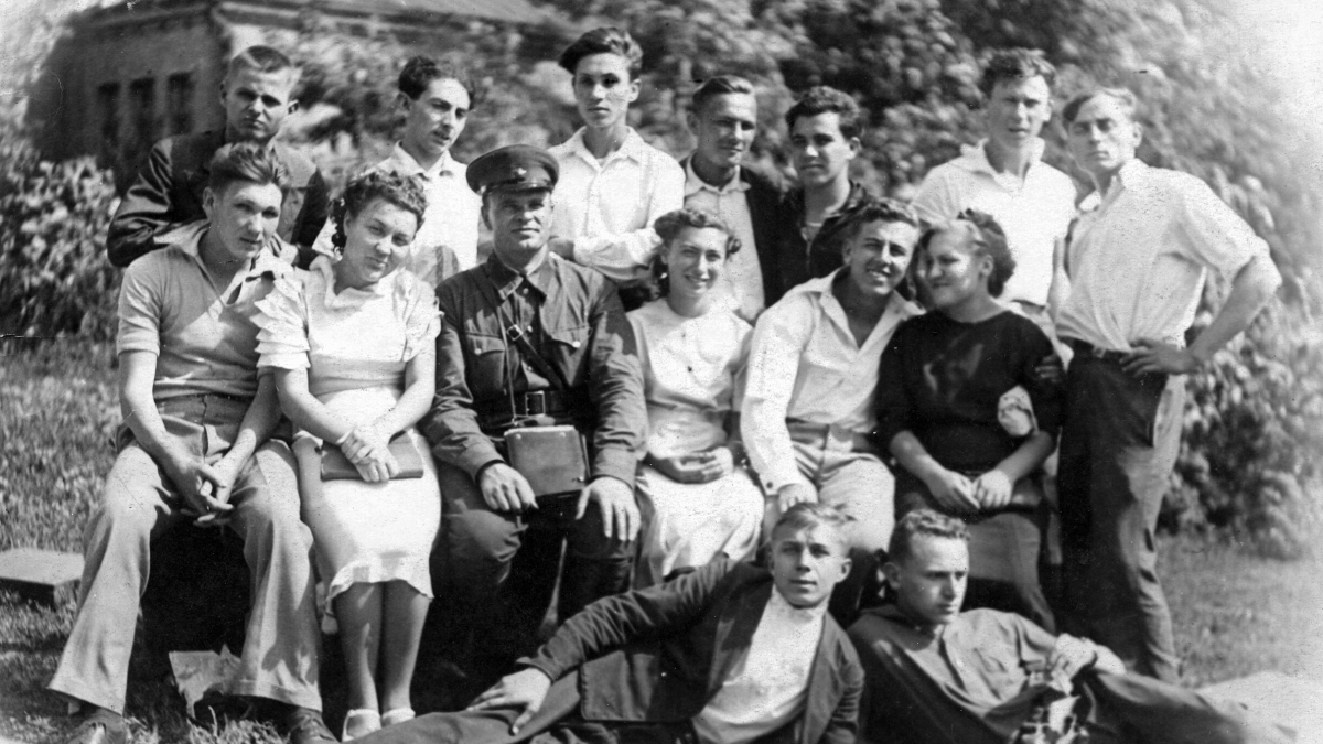 Group of young students and a soldier gathered outdoors, a historical school image during World War II.