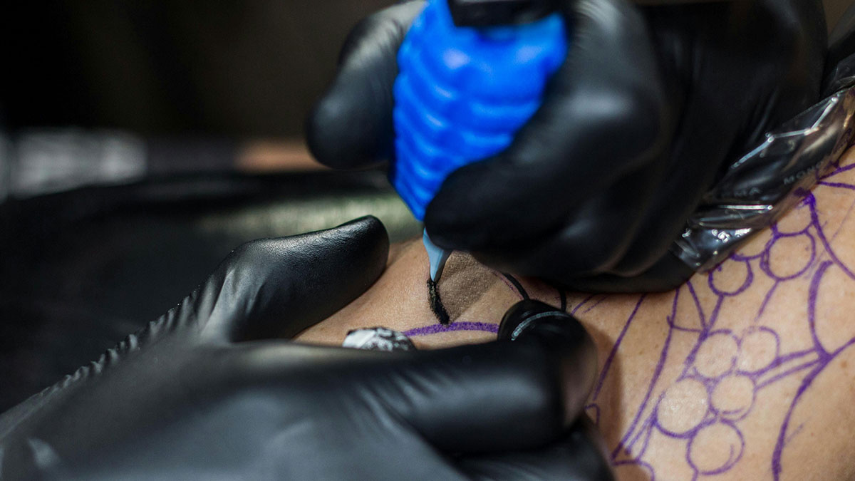 Close-up of tattoo artist's gloved hands creating a detailed tattoo, illustrating wild and embarrassing drinking stories theme.