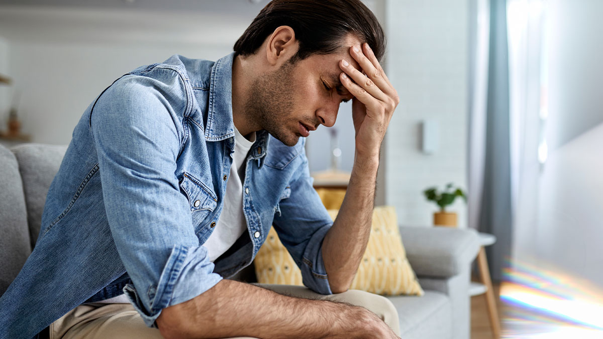 Man wrongfully jailed looking distressed sitting on sofa in a living room reflecting on wrongful imprisonment.