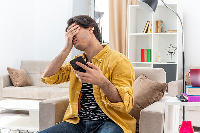 Man in yellow shirt holding phone and covering face, stressed about friend wife drunk hookup with another man at home. Man in yellow shirt holding phone and covering face, stressed about friend wife drunk hookup with another man at home.