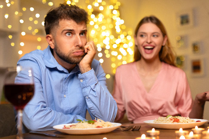 Man looking frustrated on a date with a woman at a candlelit dinner, hiding a horrible reason for cutting it short. Man looking frustrated on a date with a woman at a candlelit dinner, hiding a horrible reason for cutting it short.