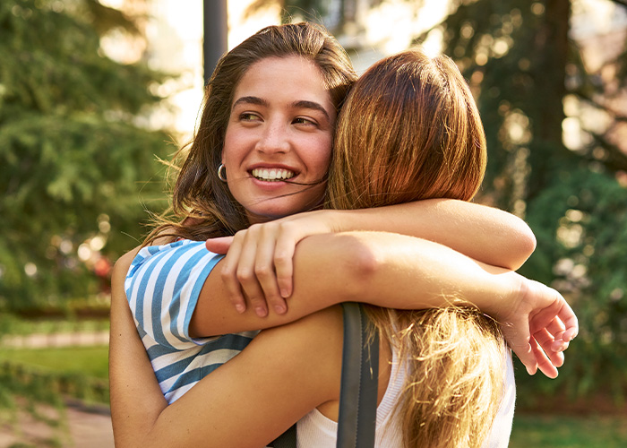 Two women hugging outdoors, illustrating a bride asking if she’s wrong for refusing SIL’s service dog at her wedding.