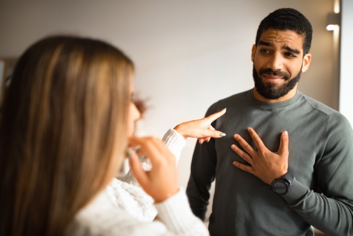 Woman pointing accusingly at man who looks apologetic during a tense conversation about babysitting responsibility. Woman pointing accusingly at man who looks apologetic during a tense conversation about babysitting responsibility.