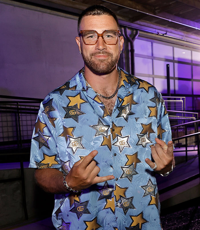 Travis Kelce wearing star-patterned shirt and clear glasses, posing casually as fans react to Taylor Swift video answer. Travis Kelce wearing star-patterned shirt and clear glasses, posing casually as fans react to Taylor Swift video answer.
