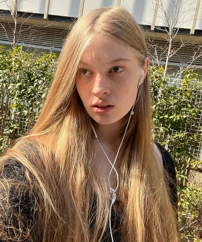 Young woman with long blonde hair wearing earbuds, outdoors with greenery, representing Elon Musk’s transgender daughter. Young woman with long blonde hair wearing earbuds, outdoors with greenery, representing Elon Musk’s transgender daughter.