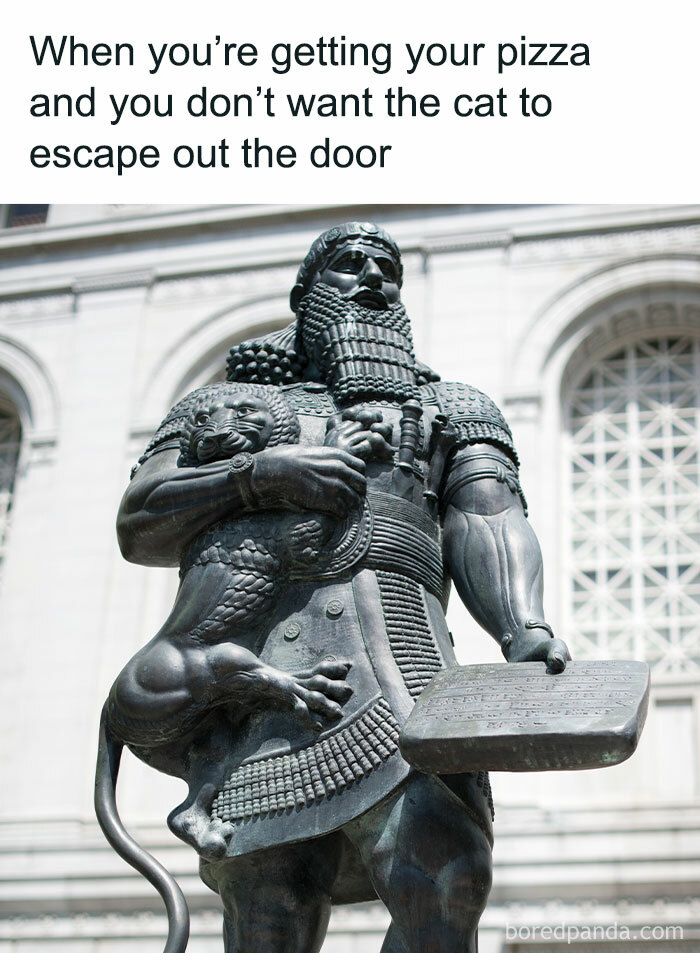 Statue of a medieval figure holding a large cat, showcasing the historic bond between humans and cats in medieval times.