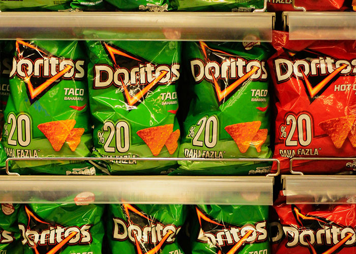 Bags of Doritos on a store shelf representing common purchases people have ditched due to ridiculous price tags.