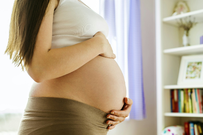 Pregnant woman gently holding belly in softly lit room, highlighting challenges faced by husband and baby in family dynamics. Pregnant woman gently holding belly in softly lit room, highlighting challenges faced by husband and baby in family dynamics.