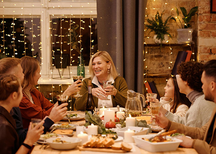 Family gathered at a baby shower, woman smiling and holding a glass while sharing a joyful moment with relatives. Family gathered at a baby shower, woman smiling and holding a glass while sharing a joyful moment with relatives.