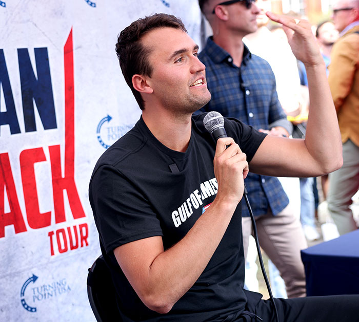 Man speaking into microphone at an event, discussing the Jimmy Fallon and Jimmy Kimmel show suspension topic. Man speaking into microphone at an event, discussing the Jimmy Fallon and Jimmy Kimmel show suspension topic.