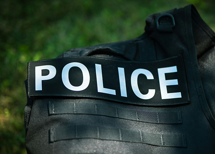 Police tactical vest with police patch resting on grass, related to cop opens fire and self-defense debate. Police tactical vest with police patch resting on grass, related to cop opens fire and self-defense debate.