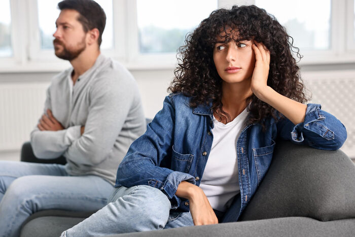 Couple sitting apart on couch looking upset and distant, illustrating the moment they realized they had fallen out of love.