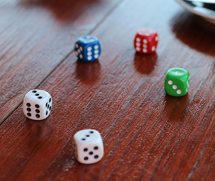 Dice of various colors on a wooden surface illustrating Brooklyn midwife’s dice game club and safety concerns for non-white women.