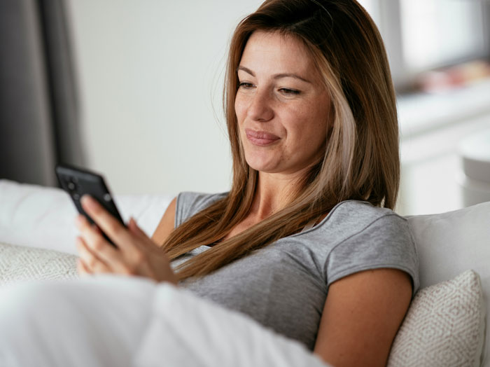 Woman sitting on couch looking at phone with a glance that hints the ick fast from a surprising phone moment.