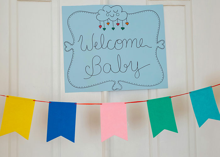 Welcome Baby sign and colorful banners hanging on door for baby shower celebration. Welcome Baby sign and colorful banners hanging on door for baby shower celebration.