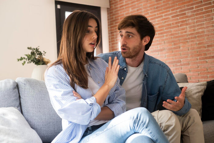A young couple sitting on a couch having a serious conversation, depicting the moment they realized they fell out of love.