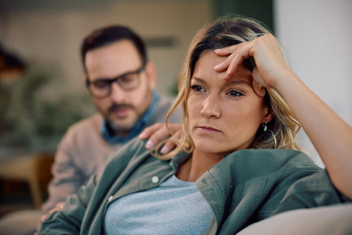 Woman looking distant and upset while man tries to comfort her, illustrating the moment they fell out of love.