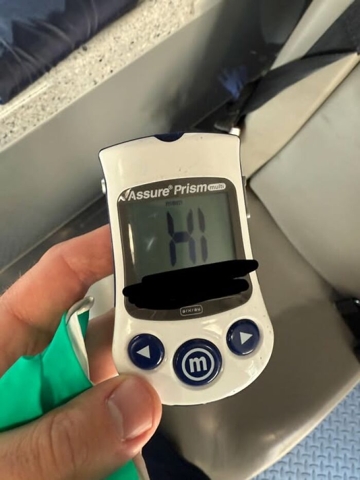 Hand holding an Assure Prism multi medical device showing "HI" on screen, relevant to EMT and paramedic humor.