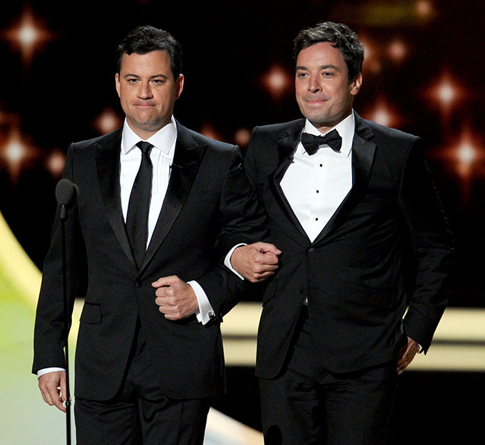 Jimmy Fallon and Jimmy Kimmel in black tuxedos appearing on stage together at a formal event, highlighting show suspension talks. Jimmy Fallon and Jimmy Kimmel in black tuxedos appearing on stage together at a formal event, highlighting show suspension talks.