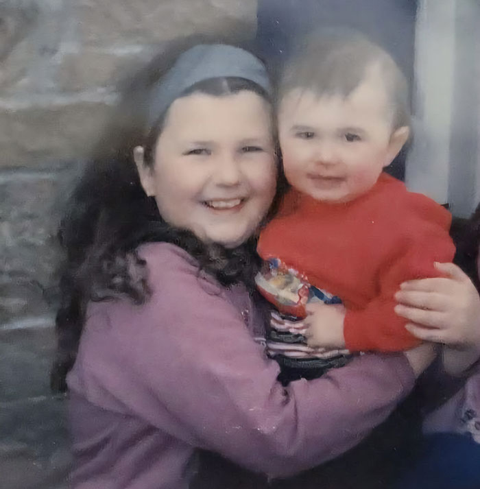 Young girl smiling and holding a toddler in a red sweater, related to American Nightmare mom who married man she met online. Young girl smiling and holding a toddler in a red sweater, related to American Nightmare mom who married man she met online.