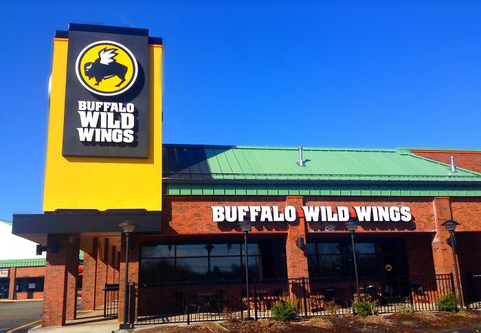 Buffalo Wild Wings restaurant exterior under clear blue sky, featuring signage and outdoor patio area.