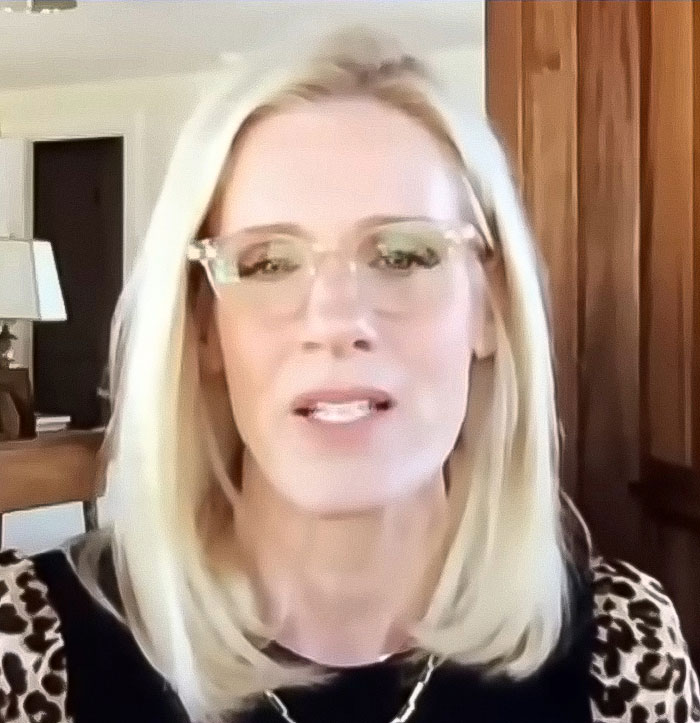 Blonde woman with glasses speaking indoors about husband of woman caught with CEO amid divorce news. Blonde woman with glasses speaking indoors about husband of woman caught with CEO amid divorce news.