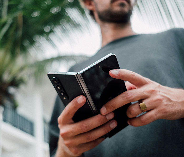 Man holding a Samsung foldable phone outdoors, highlighting Samsung mocking new iPhone after Apple launch. Man holding a Samsung foldable phone outdoors, highlighting Samsung mocking new iPhone after Apple launch.