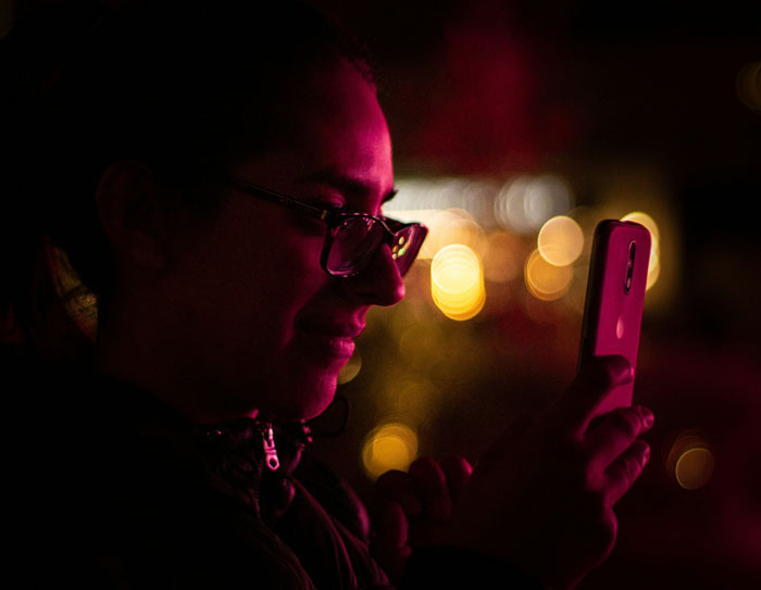 Person wearing glasses looking at phone in dim light, capturing moment when a glance at a phone changed everything.