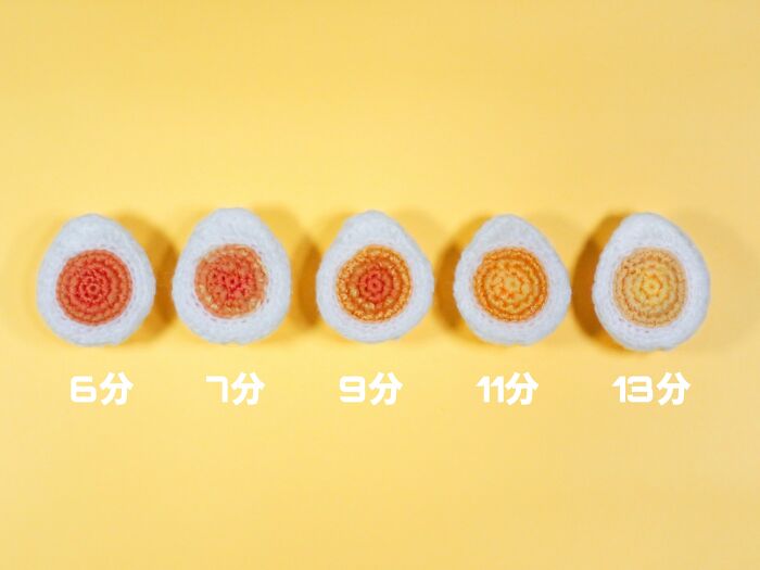 Crocheted realistic food-inspired accessories resembling soft-boiled eggs arranged on a yellow background.