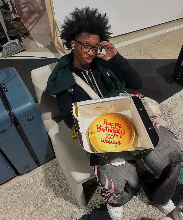 Young man holding birthday cake sitting on a chair near luggage, related to abandoned Tesla registered to singer news story Young man holding birthday cake sitting on a chair near luggage, related to abandoned Tesla registered to singer news story