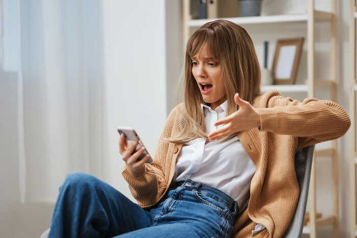 Woman reacting with shock to a message on her phone, illustrating childish reasons ladies ditched a guy in dating scenarios.