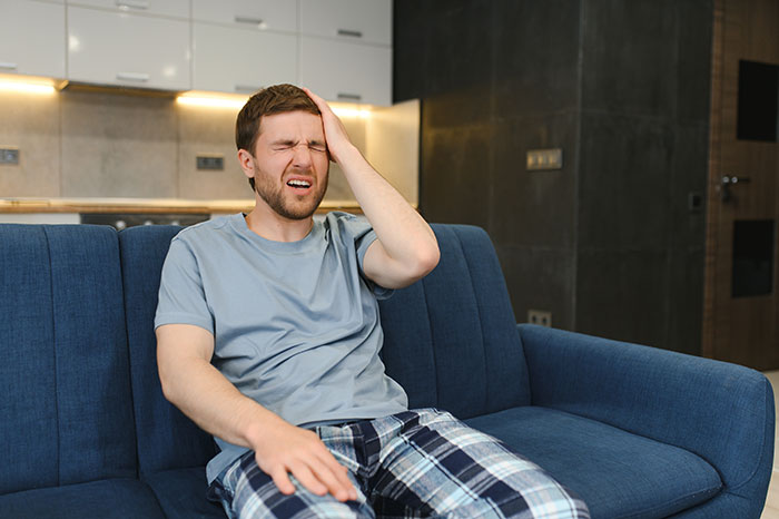 Man sitting on couch looking frustrated while his girlfriend’s son has a meltdown about mountain biking early morning. Man sitting on couch looking frustrated while his girlfriend’s son has a meltdown about mountain biking early morning.