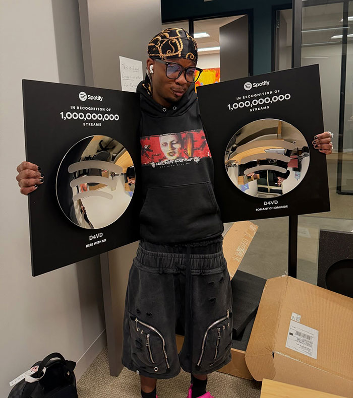 Singer holding two Spotify plaques for 1 billion streams, relating to decomposing body found in abandoned Tesla case. Singer holding two Spotify plaques for 1 billion streams, relating to decomposing body found in abandoned Tesla case.