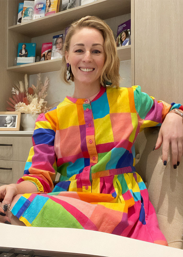 Woman smiling in colorful dress sitting indoors, related to doctor furious after Virgin Australia staff incident breastfeeding pump. Woman smiling in colorful dress sitting indoors, related to doctor furious after Virgin Australia staff incident breastfeeding pump.