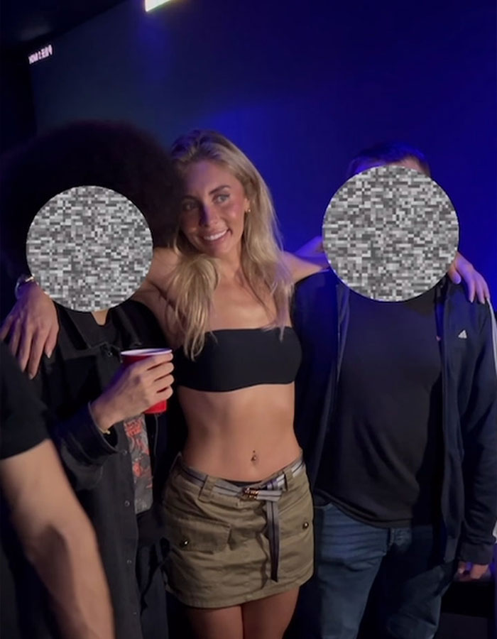 Adult star Bonnie Blue smiling at nightclub event with two individuals against dark blue background. Adult star Bonnie Blue smiling at nightclub event with two individuals against dark blue background.