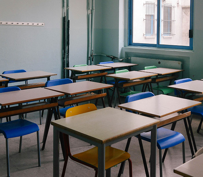 Empty classroom with desks and chairs in a school setting related to teacher arrested for using poop spray and causing damage. Empty classroom with desks and chairs in a school setting related to teacher arrested for using poop spray and causing damage.