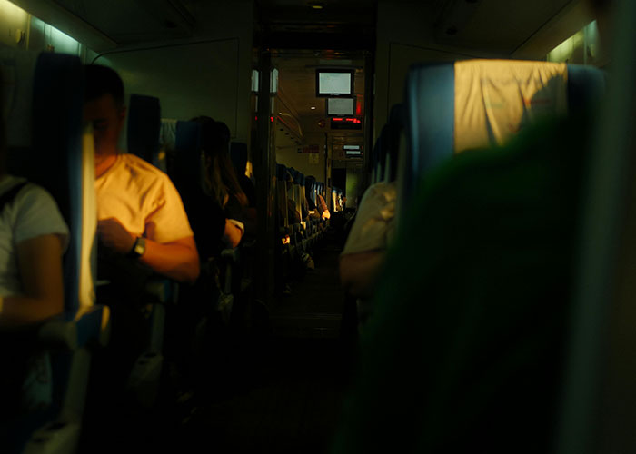 Airplane interior with passengers seated, dim lighting, illustrating a flight attendant’s seatbelt extender dilemma. Airplane interior with passengers seated, dim lighting, illustrating a flight attendant’s seatbelt extender dilemma.