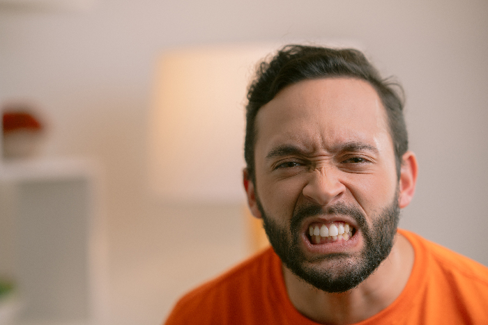 Angry man with beard in an orange shirt expressing frustration, related to husband calls pregnant wife and baby issues. Angry man with beard in an orange shirt expressing frustration, related to husband calls pregnant wife and baby issues.