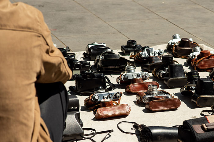 Person sitting near a collection of vintage cameras and leather cases, highlighting the inclusion of AI into everything trend.