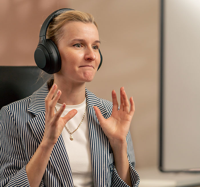 Woman wearing headphones, gesturing with hands, focused on discussing the inclusion of AI in modern trends.