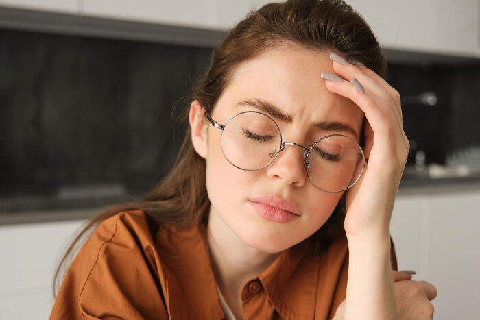 Young woman wearing glasses, looking distressed and reflective, illustrating the moment of falling out of love.