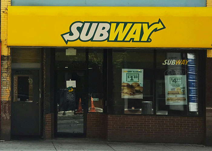 Subway restaurant exterior with menu signs highlighting prices, reflecting common purchases ditched due to high price tags.
