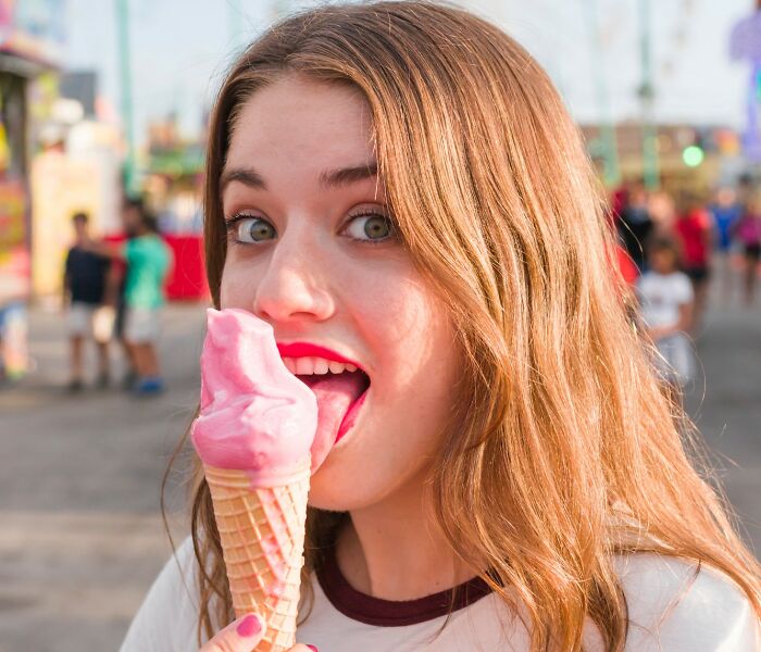Young woman enjoying pink ice cream cone outdoors, illustrating childish reasons ladies ditched a guy.